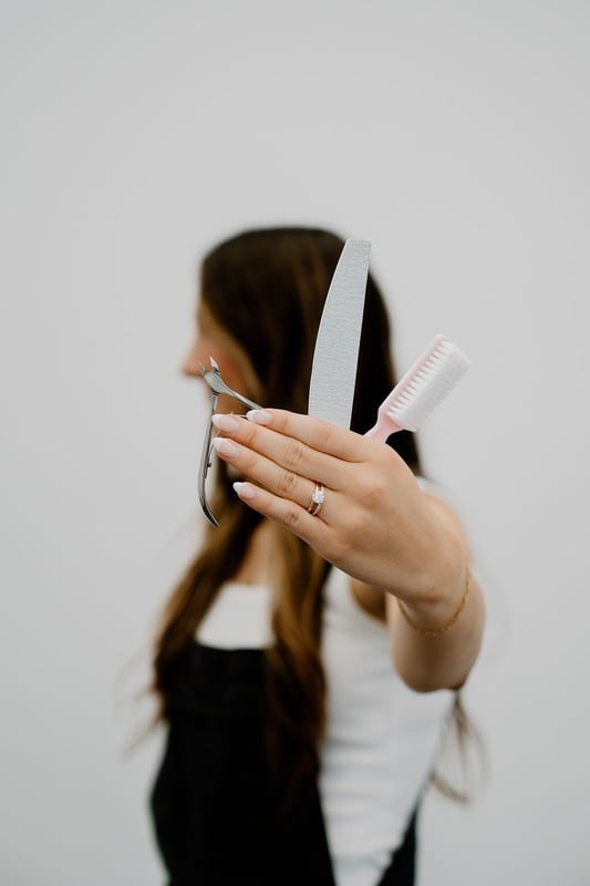 Kami holding a cuticle nipper, file, and brush